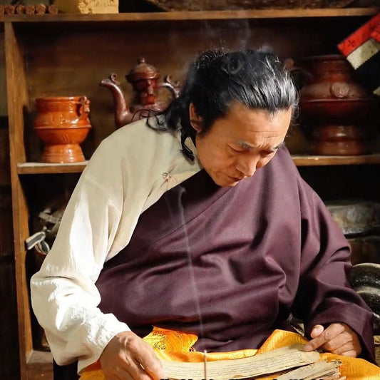 A rich, authentic portrait of 18th-generation master Sang Ju in traditional Tibetan attire holding a freshly prepared bundle of hand-rolled incense sticks tied with red string.